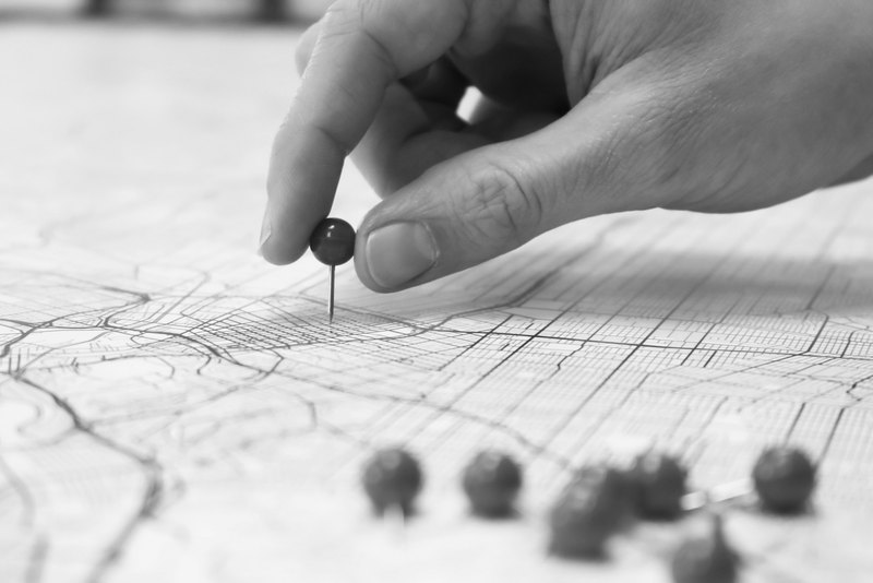 Una mano clava un alfiler en el plano de una ciudad
