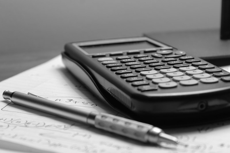 Una calculadora y un portaminas sobre una hoja con cuentas a mano