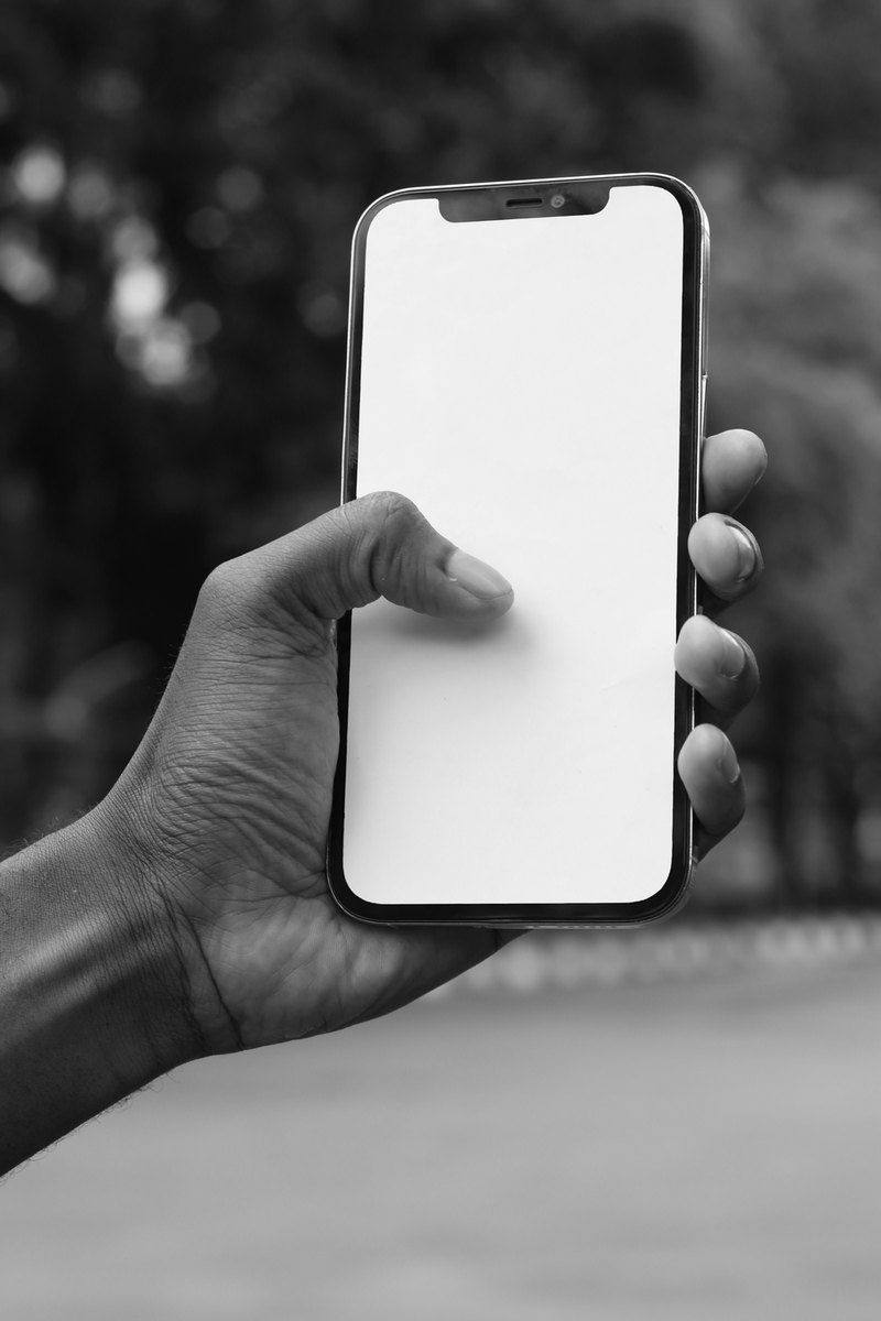 Una mano sostiene un celular con la pantalla en blanco