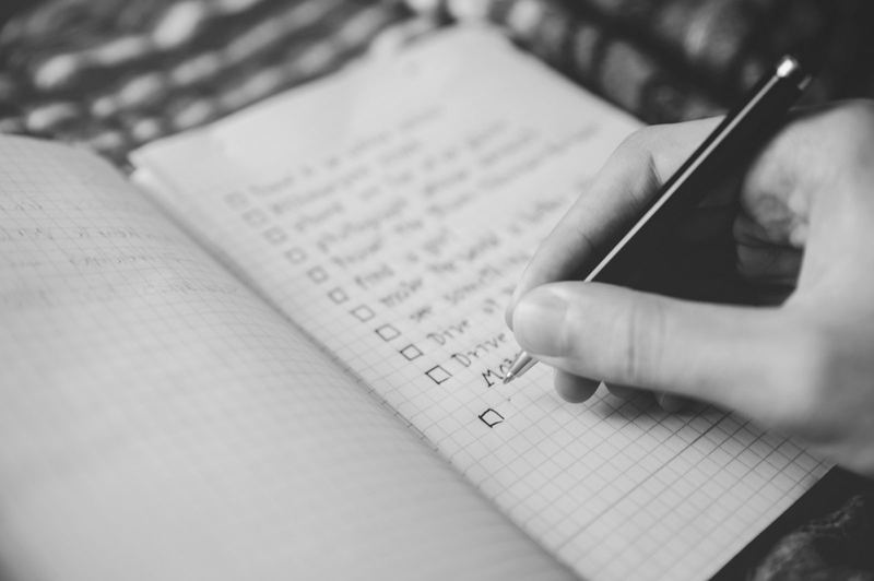Una mano escribe una lista de casillas en un cuaderno