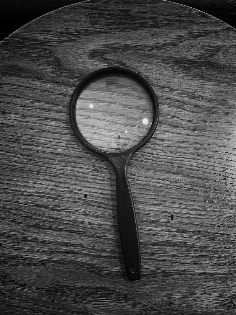 Una lupa de marco negro sobre una mesa de madera